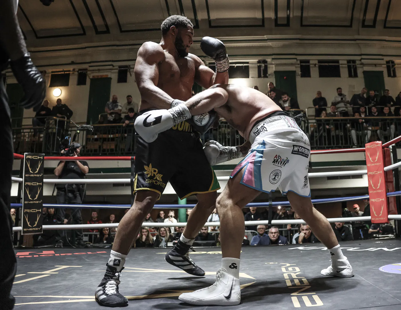 Boxing match in progress inside the ring with Rich Energy branding on the corner pads